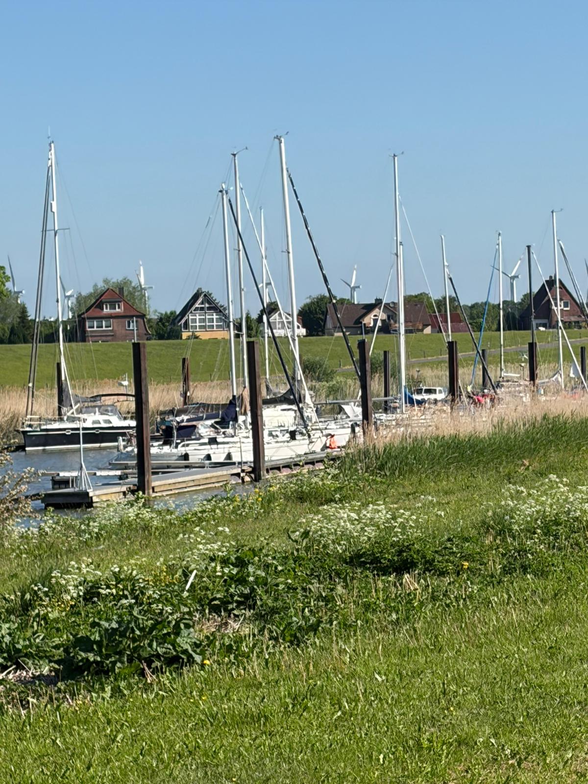 Bootshafen am Deich mit Blick auf Häuser und Windräder